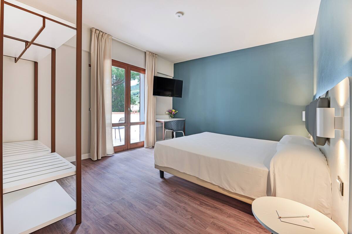 Una habitación de hotel con cama, escritorio, silla y televisor.