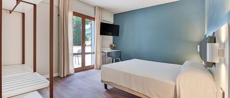 Una habitación de hotel con cama, escritorio, silla y televisor.