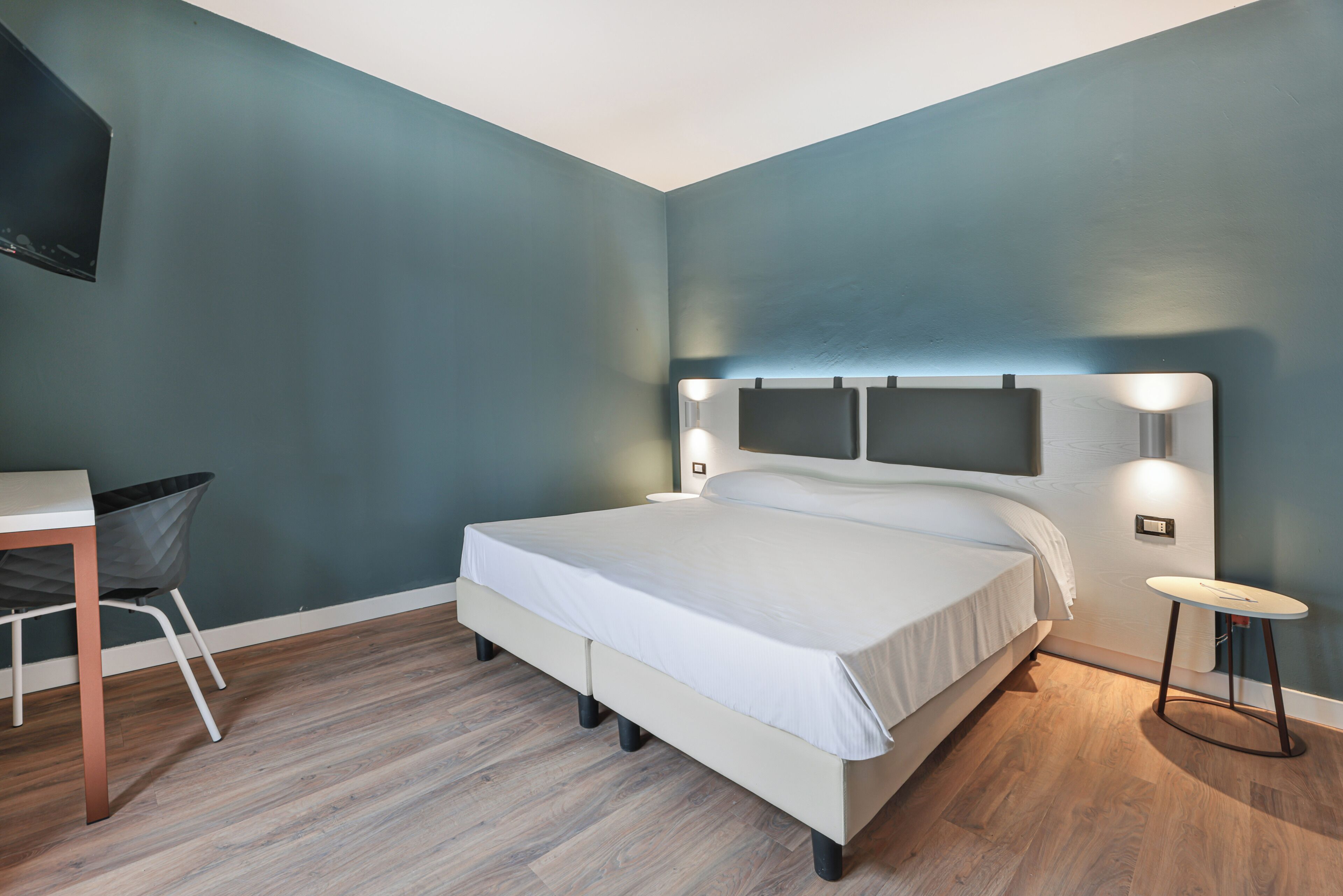 A bedroom with a bed, bedside table, and a chair.