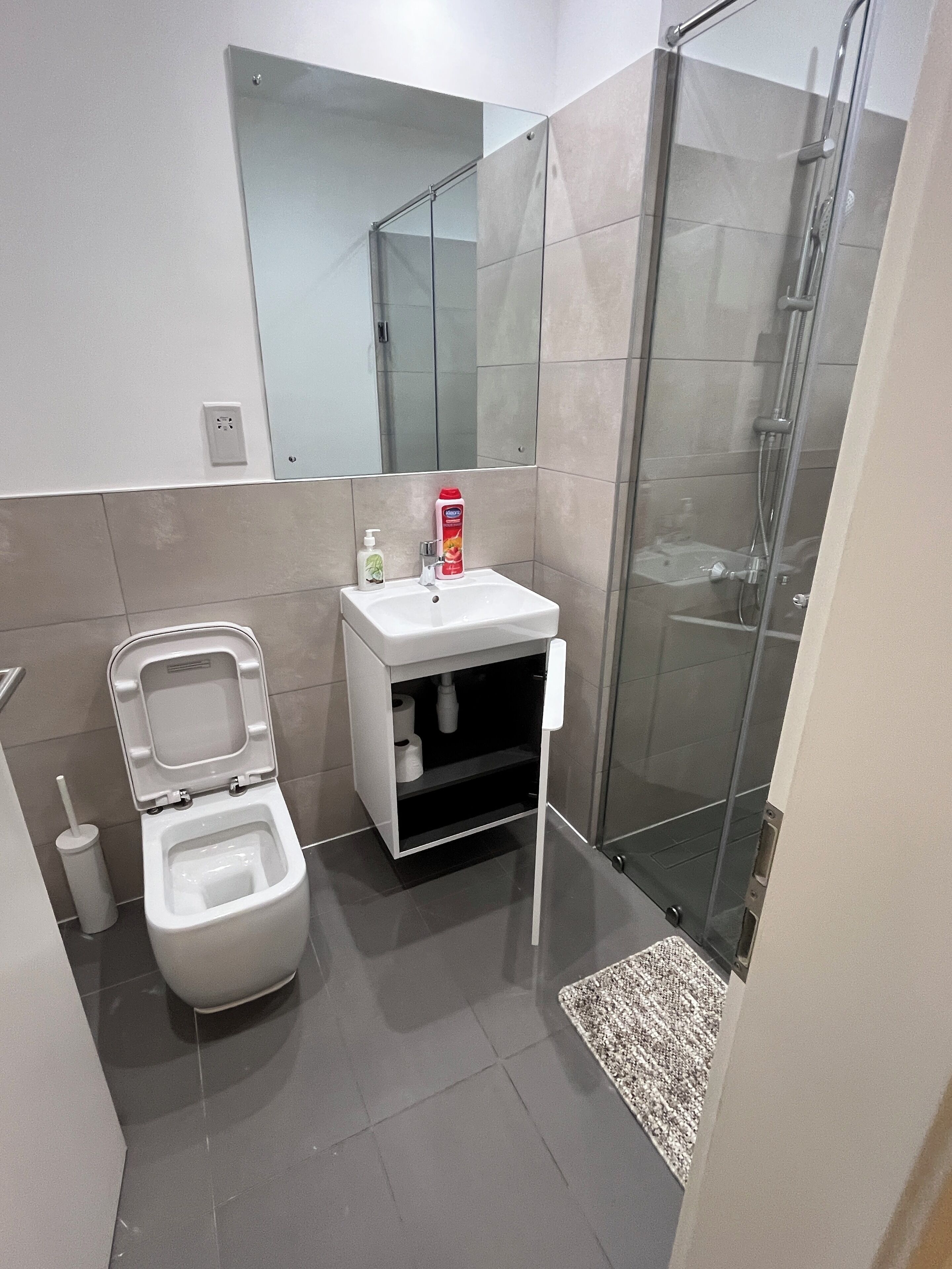 A modern bathroom with a toilet, sink, and glass shower enclosure.