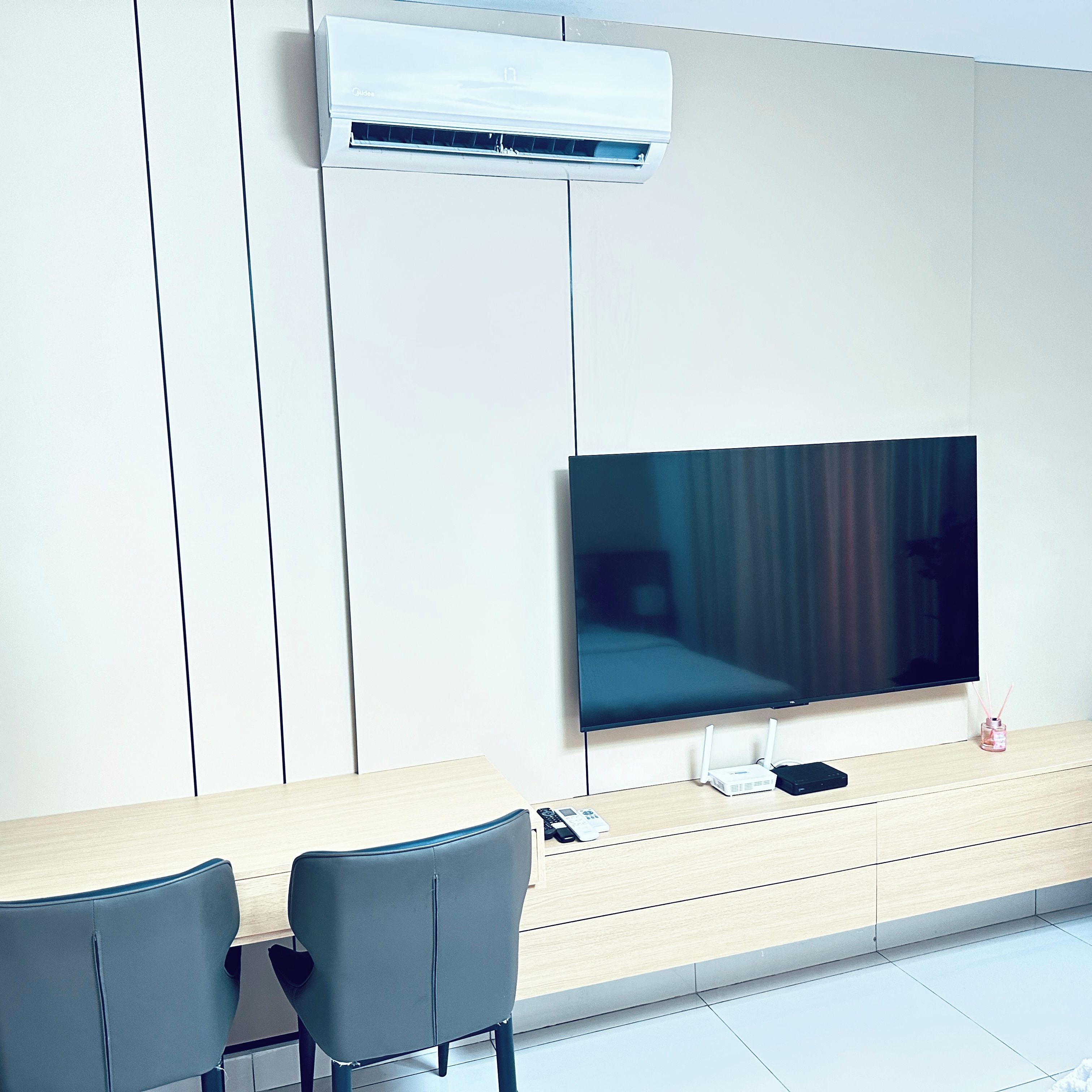 Ein modernes Hotelzimmer mit einem flachbildfernseher an der Wand, einem Holztisch mit einem Laptop und zwei Stühlen.