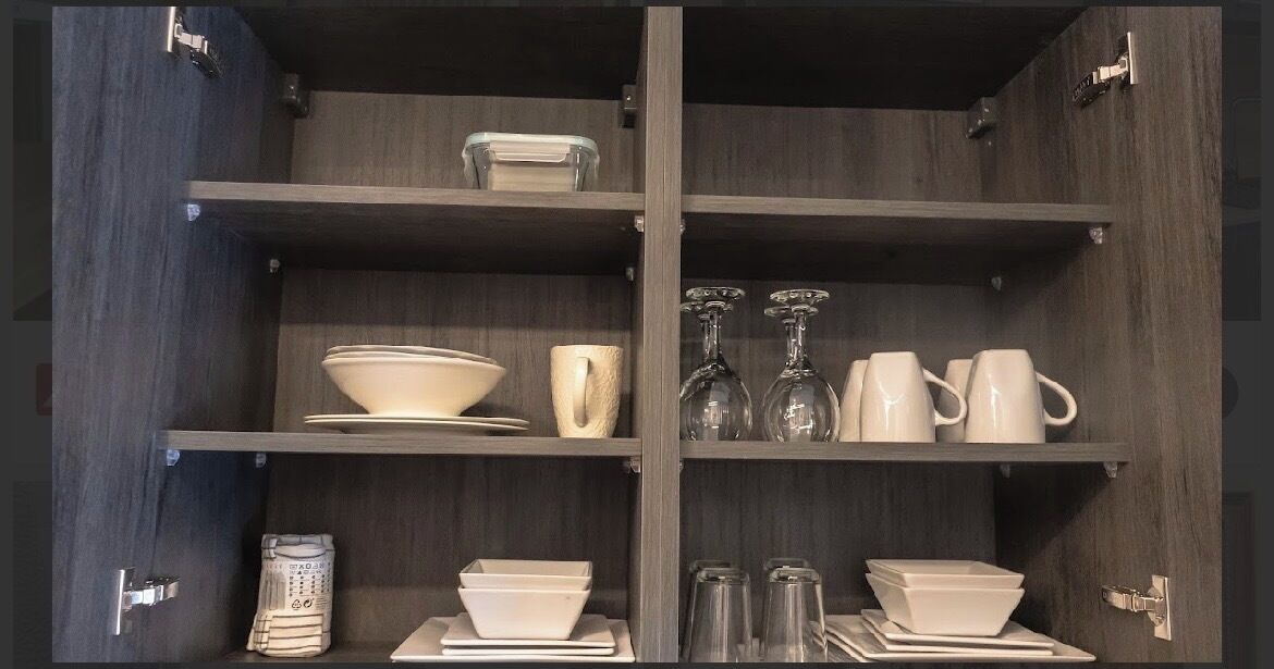 Cocina con armarios y estantes de madera que muestran diverso menaje.