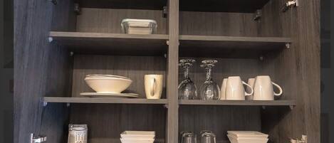 Cocina con armarios y estantes de madera que muestran diverso menaje.