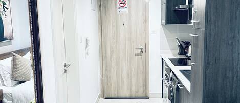Ett modernt kök med en inbyggd ugn, en matplats med bord och stolar samt en hall som leder till en dörr med en skylt som säger ”Rökning förbjuden”.