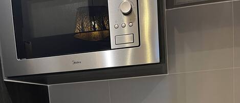 A kitchen with a microwave, toaster, kettle, and a black induction cooktop.