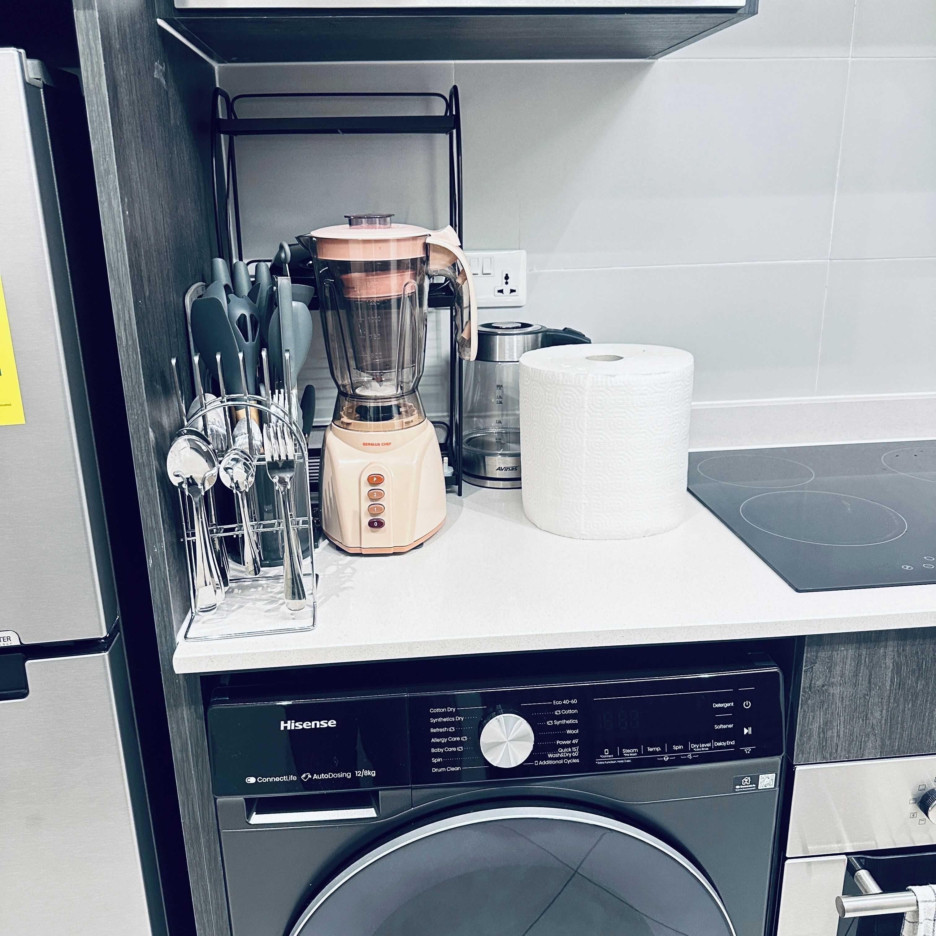 Une cuisine équipée d’un lave-linge, d’un mixeur et d’un rouleau d’essuie-tout.