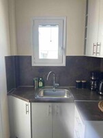 Uma cozinha moderna com uma pia de aço inoxidável, uma janela acima da pia e armários com puxadores.