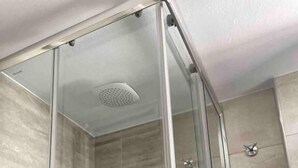 En duschkabin med glasväggar och en modern design, ett synligt duschmunstycke och en kontrollpanel.