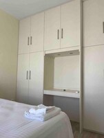 Um quarto com cama, guarda-roupa e espelho.