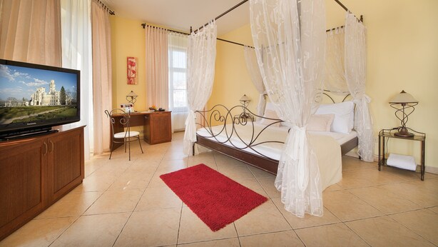 A bedroom with a four-poster bed, a TV, a desk, and a chair. - Residence Knížecí Dvůr (Hluboká nad Vltavou)