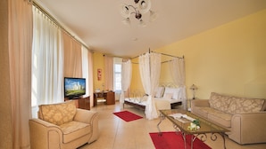 A living room with a sofa, a coffee table, a TV, and a bed with a canopy. - Residence Knížecí Dvůr (Hluboká nad Vltavou)