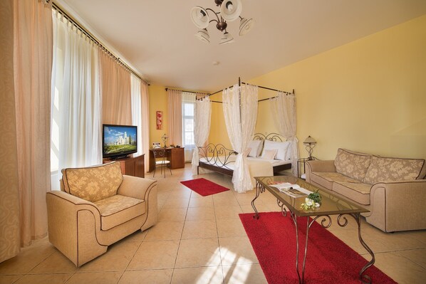 A living room with a sofa, a coffee table, a TV, and a bed with a canopy. - Residence Knížecí Dvůr (Hluboká nad Vltavou)