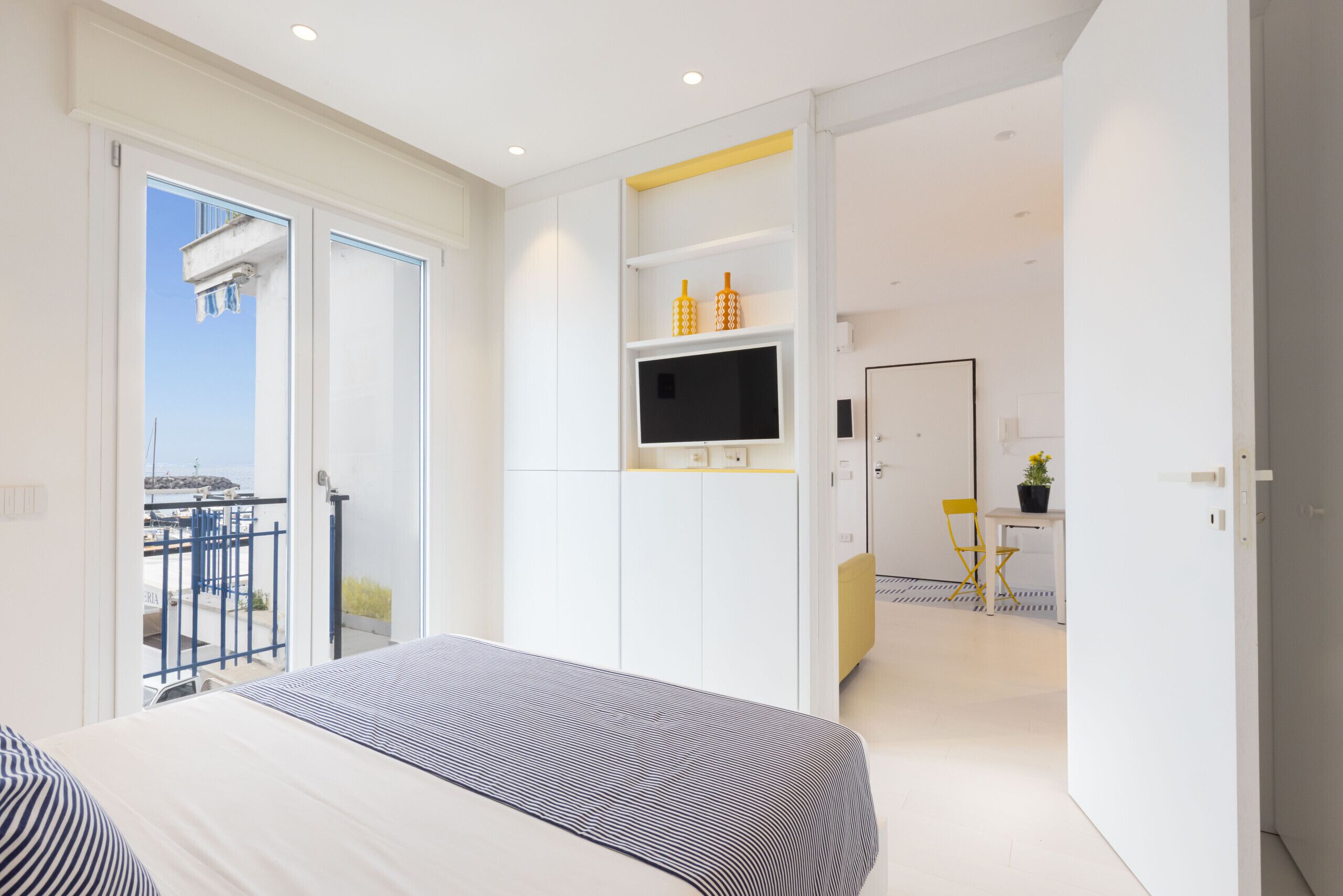 Una habitación de hotel moderna con cama, televisor y balcón con vistas.