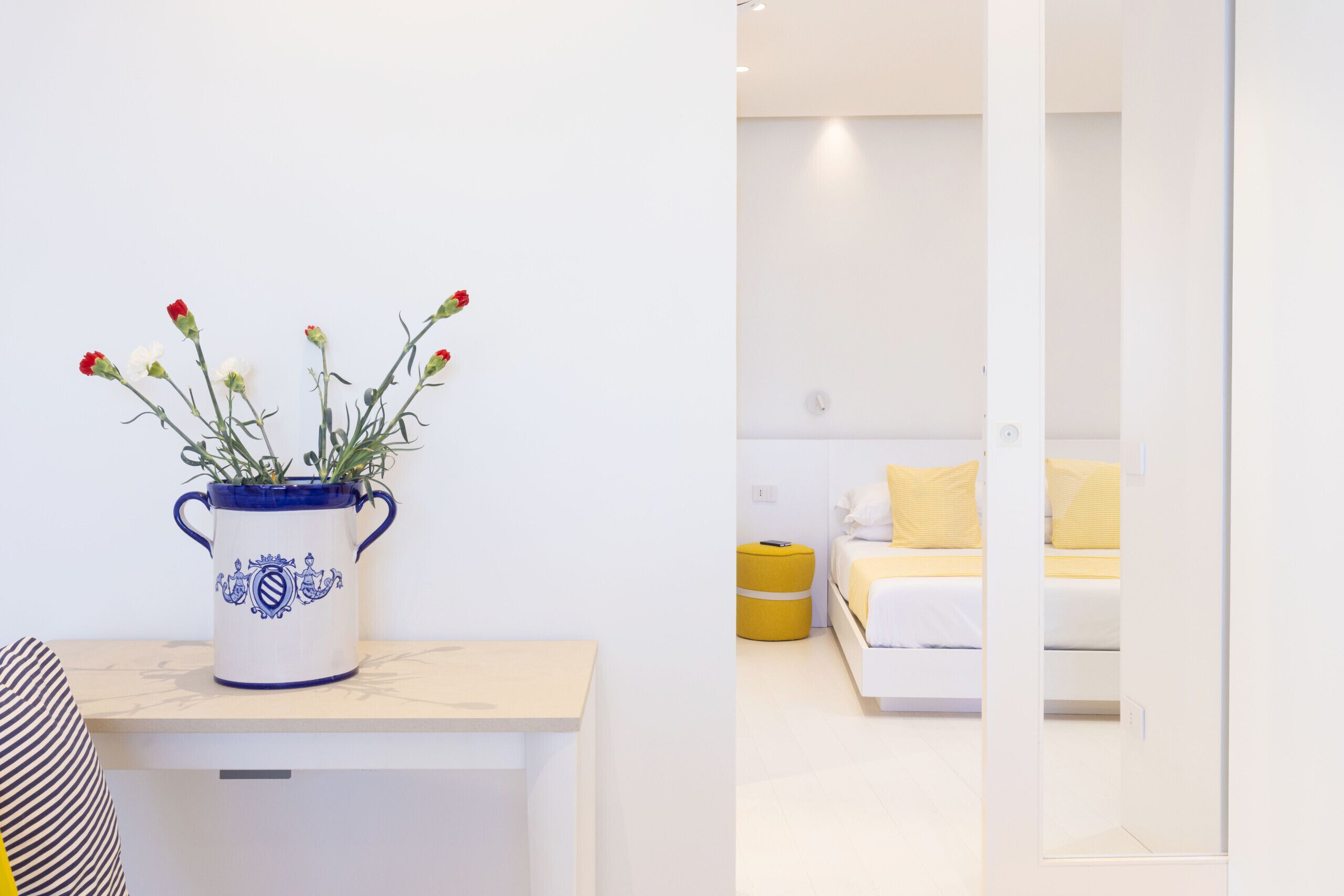 A modern bedroom with a bed, a bedside table, and a vase with flowers.