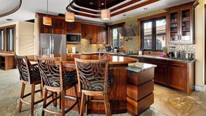 Cucina spaziosa con isola centrale, sgabelli da bar in legno e un'ampia finestra che garantisce luce naturale.