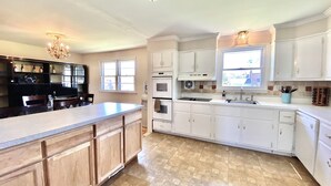 A spacious kitchen with a large island, white cabinetry, and a tiled floor. - Spacious 5-bedroom house in welcoming Wilmington with WiFi, AC, Large Yard (Wilmington)