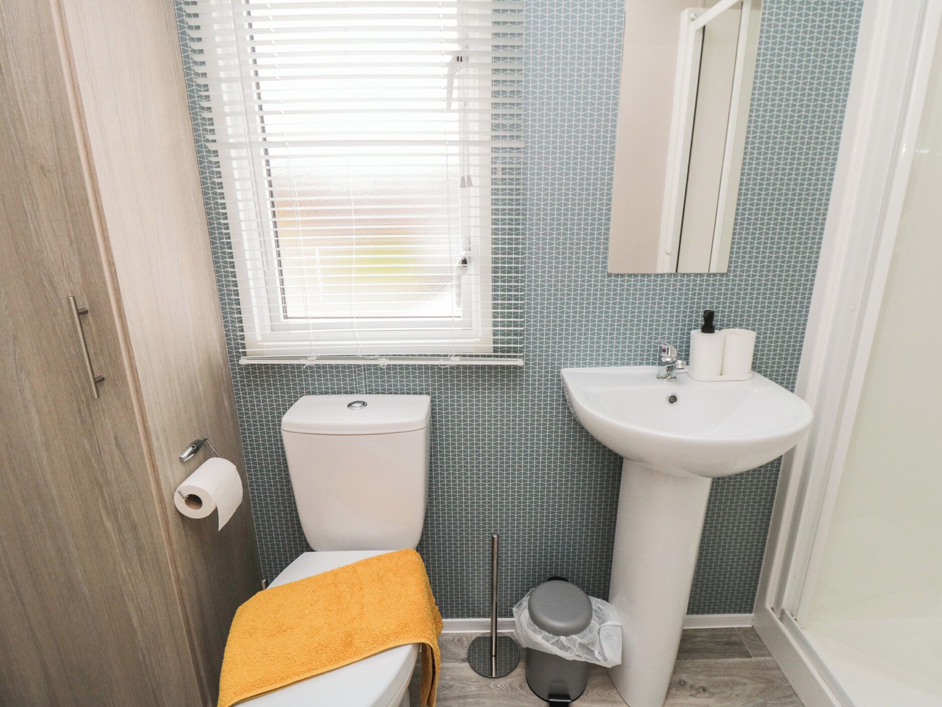 A small bathroom with a toilet, sink, and window.