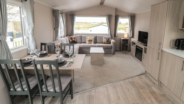 A compact living space with a dining area, sofa, TV, and kitchen. - Meadow View (Morpeth)
