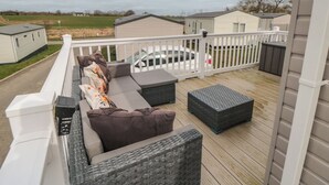 A deck with a sofa, ottoman, and a small table. - Meadow View (Morpeth)
