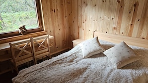 A wooden room with a bed, a window, and a chair.