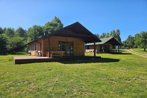 Eine Holzhütte mit Veranda und überdachter Außenbereich mit Sitzgelegenheit.