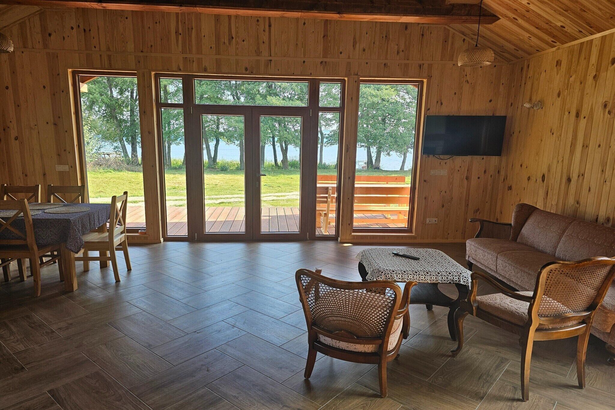 Un interior de madera con comedor, sofá y televisor.