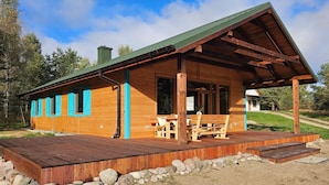 A wooden cabin with a porch, a dining table, and benches.