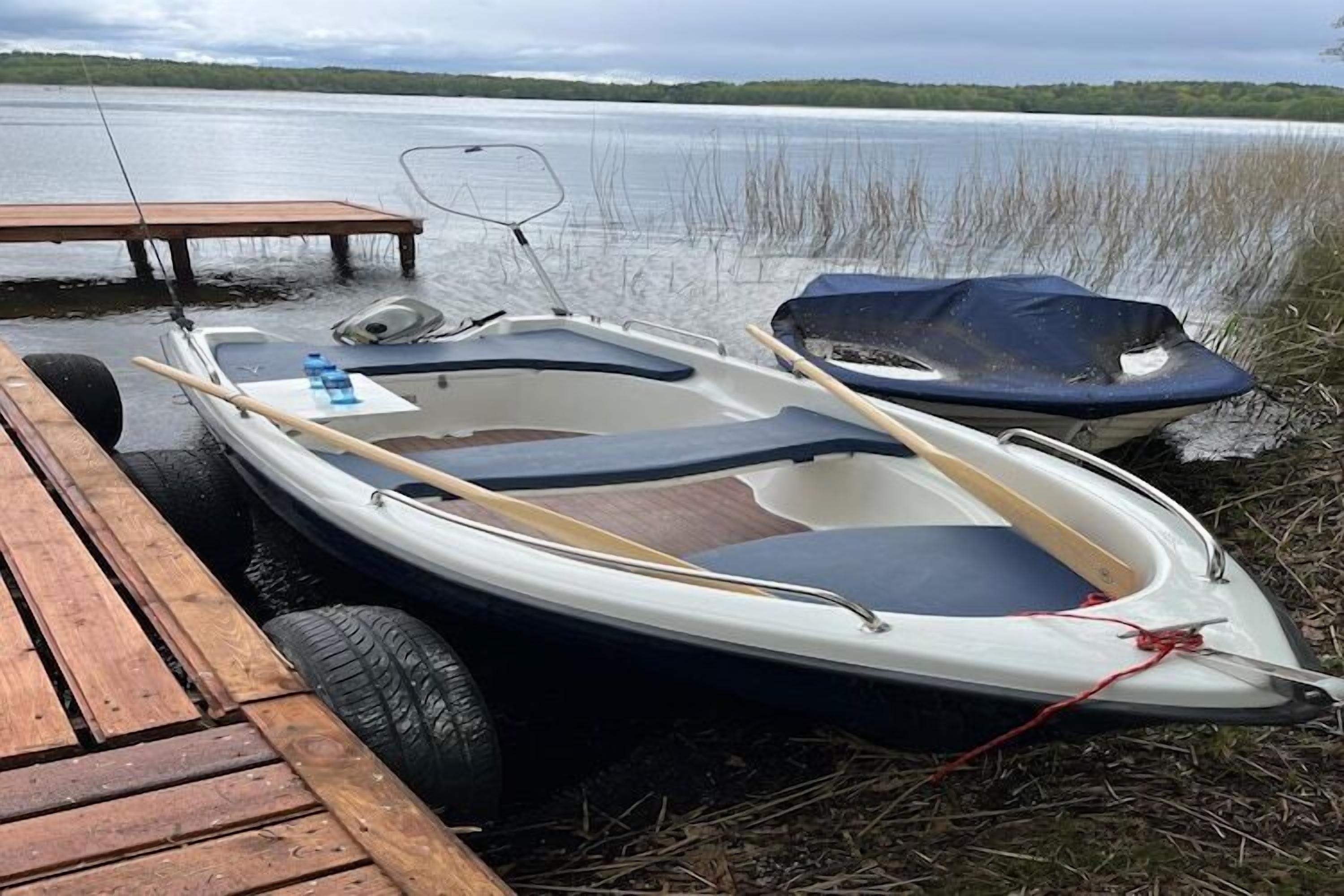 A small boat on a trailer docked at a wooden pier.