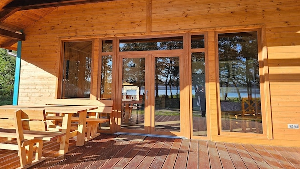 A wooden cabin with a deck, large glass doors, and outdoor seating.
