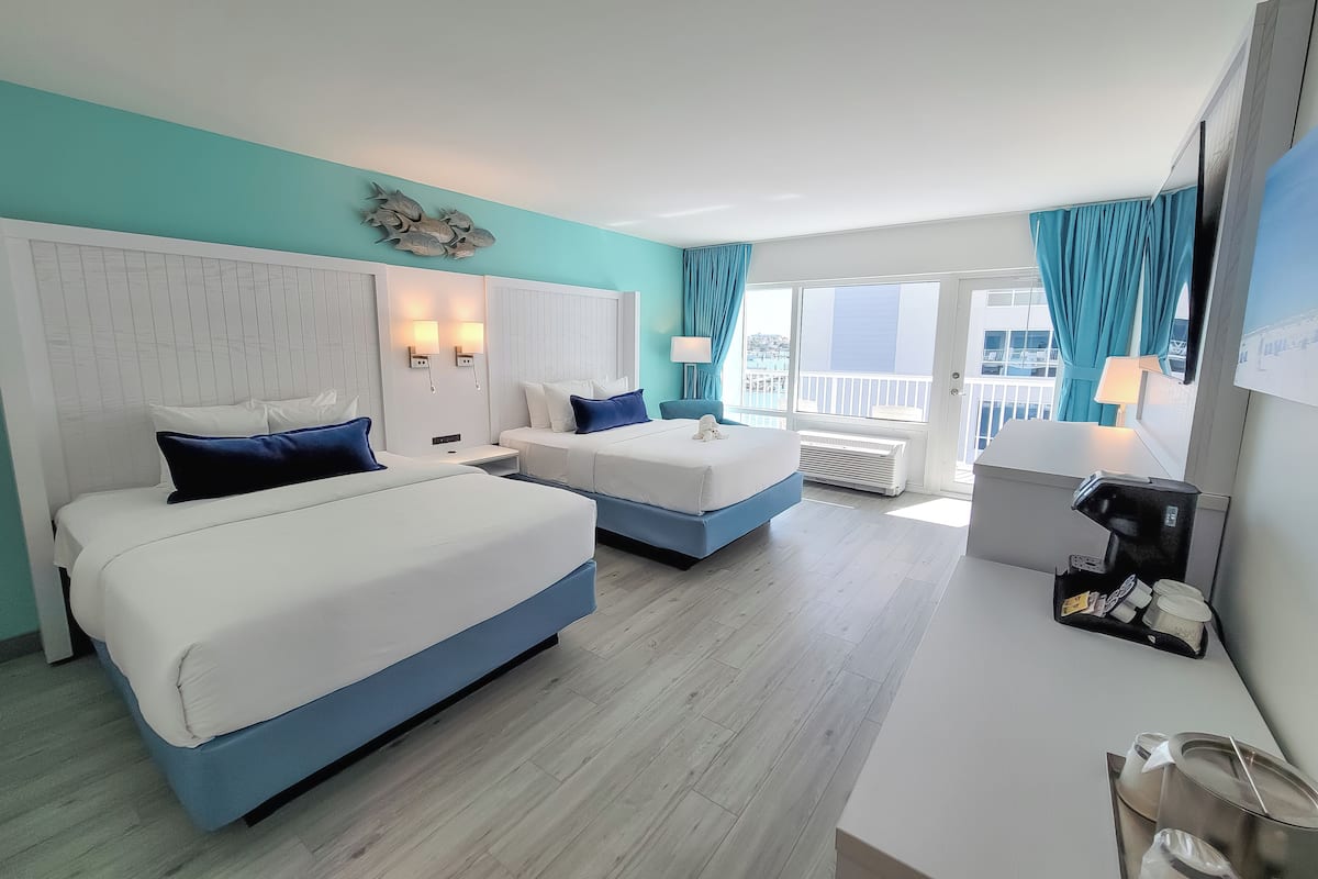 Une chambre d’hôtel avec deux lits, une grande fenêtre donnant sur un beau paysage, un balcon et un minibar.