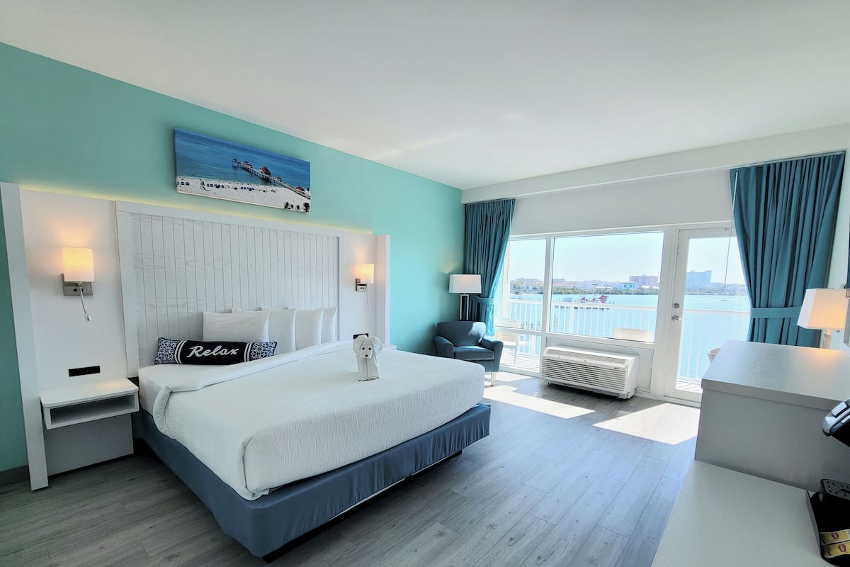 Une chambre d’hôtel avec un grand lit, une vue sur la mer et un balcon doté d’une balustrade.