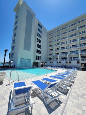 A pool area with sun loungers and a building with multiple balconies. - ChartHouse Clearwater Beach Marina Hotel (Clearwater Beach)