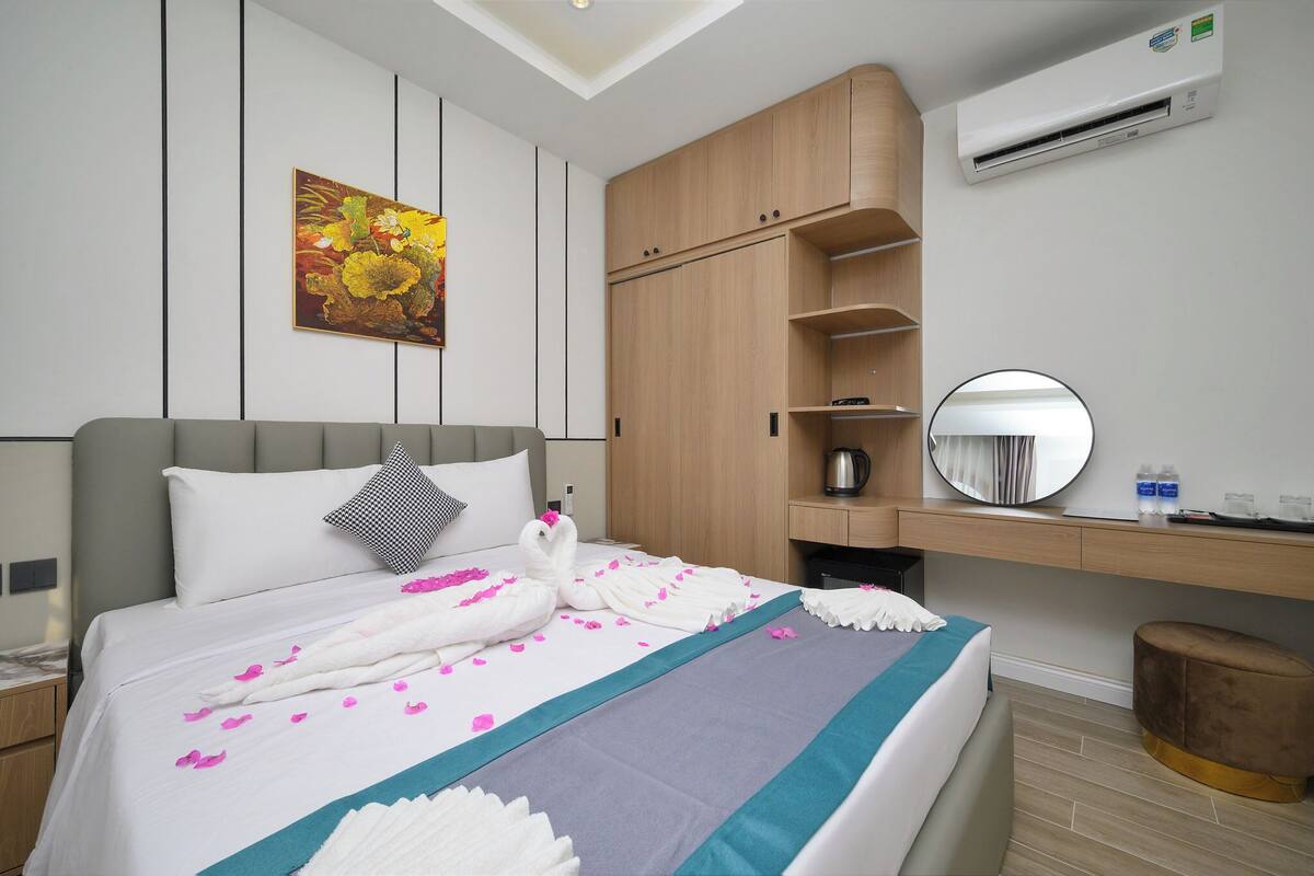 Ein modernes Hotelzimmer mit einem ordentlich bezogenen Bett, einem großen Spiegel, einem Holzschrank und einem Gemälde an der Wand.