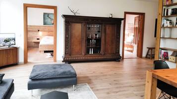 Ein modernes Wohnzimmer mit Holzboden, einem großen, dunkelbraunen Schrank mit Glastüren, einem Fernseher und einem Bücherregal.