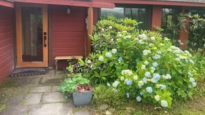 Une cabane en bois rouge avec un porche couvert et un petit banc.