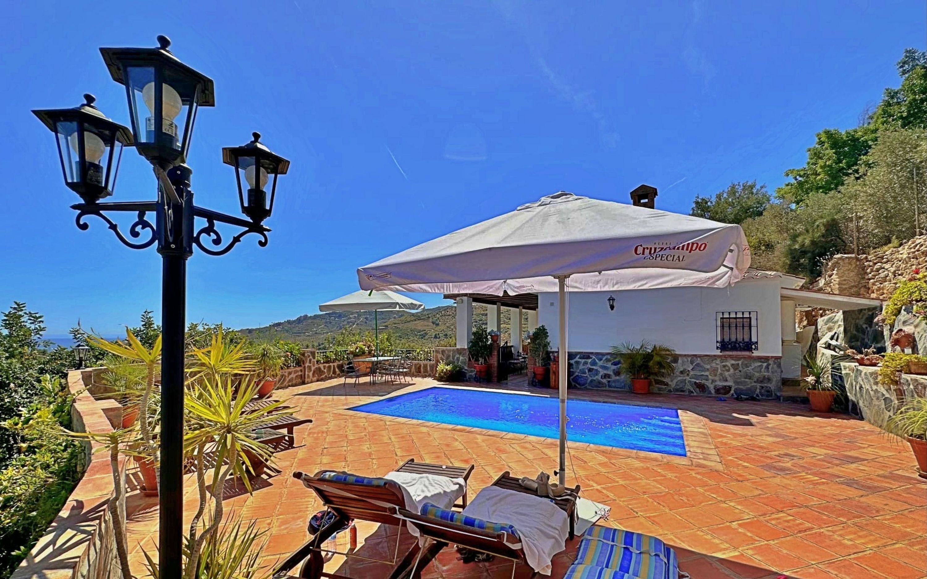 Ein Poolbereich mit Liegestühlen, einer überdachten Terrasse und Blick aufs Meer.