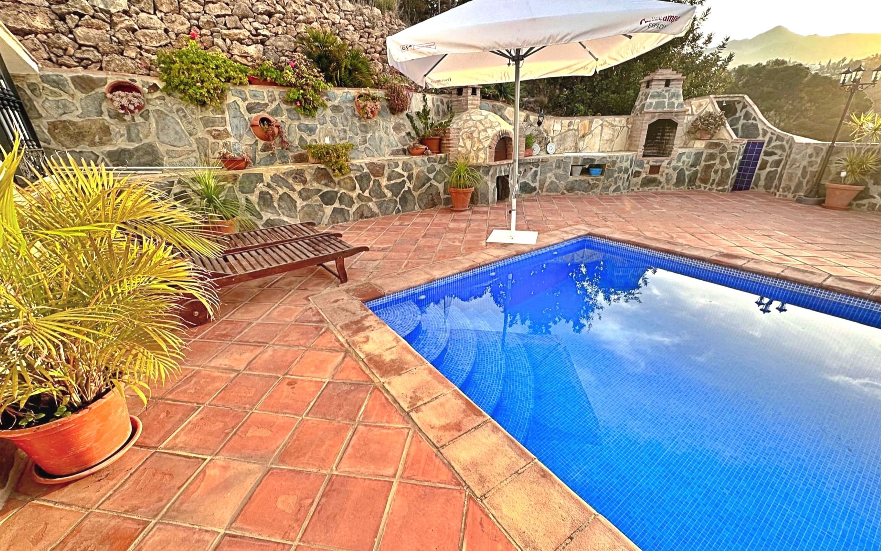 Una piscina con un muro de piedra y plantas en macetas.