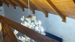 A wooden ceiling with exposed beams and a hanging light fixture.