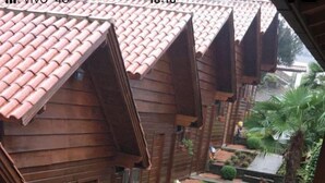 A row of wooden houses with red-tiled roofs, a narrow pathway, and small gardens.