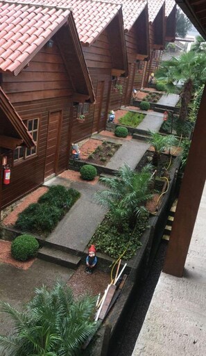 A row of wooden houses with red-tiled roofs, a narrow pathway, and small gardens. - Chalés dos Pássaros (Gramado)