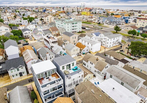 An aerial view of a residential area with various houses and buildings, including a prominent multi-story building with balconies and a flat roof.