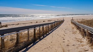 Een strandpad met houten leuningen dat naar de oceaan leidt.