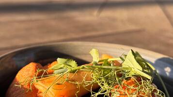 Een schaal eten met diverse ingrediënten, waaronder groenten en mogelijk wat vlees, geserveerd in een aardewerken kom.