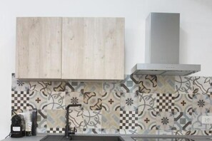 Een koelkast, een oven, een kookplaat, kookgerei, borden en bestek