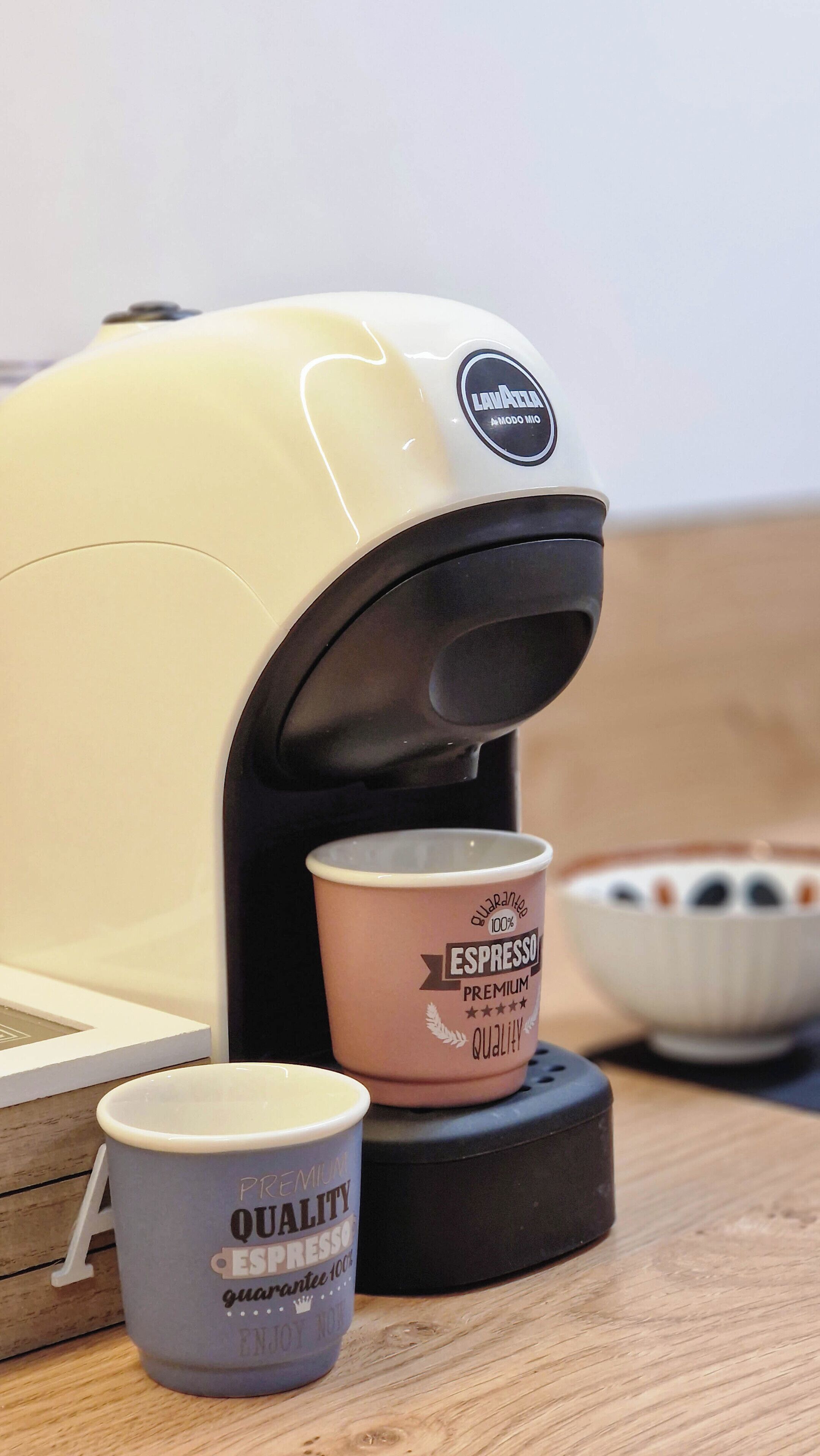 Une machine à café avec deux tasses portant les inscriptions « ESPRESSO DE QUALITÉ SUPÉRIEURE » et « ESPRESSO DE QUALITÉ ».