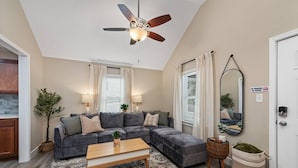 Un salon moderne avec un canapé d’angle, une table basse en bois et un ventilateur de plafond.