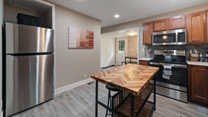 Une cuisine moderne dotée d’appareils électroménagers en acier inoxydable, de meubles en bois et d’un îlot central agrémenté de tabourets de bar.