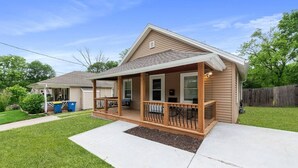 Une maison de plain-pied avec un porche à l’avant, un patio couvert et un petit jardin devant.