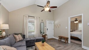 Un salon avec un canapé d’angle gris, une table basse en bois et un ventilateur de plafond.