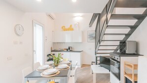 Una cocina moderna con armarios blancos, horno empotrado y microondas.